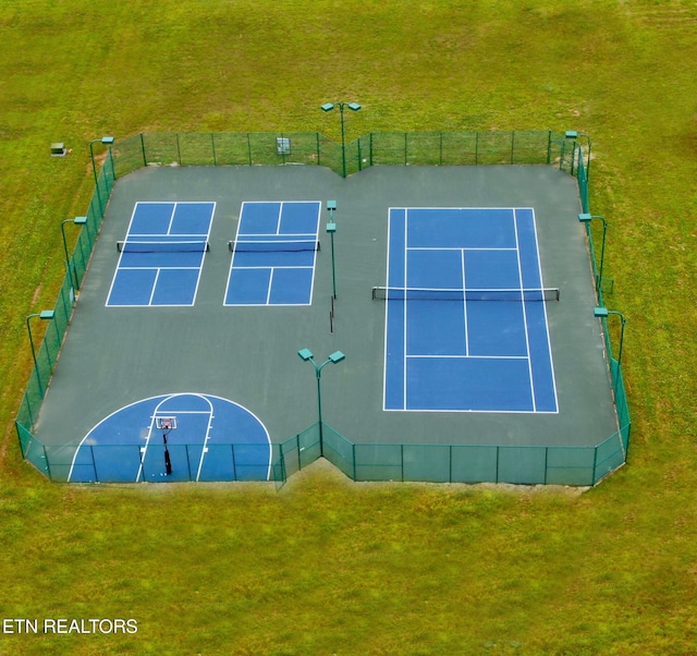 view of tennis court with fence and a lawn