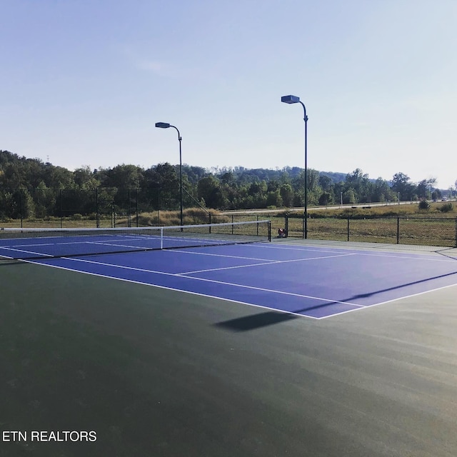 view of tennis court with community basketball court and fence
