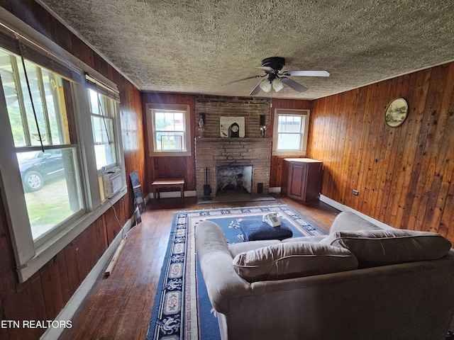 living room with hardwood / wood-style floors, a fireplace, wooden walls, and a textured ceiling