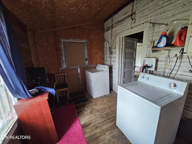 laundry area featuring dark hardwood / wood-style flooring, wooden walls, and washing machine and clothes dryer