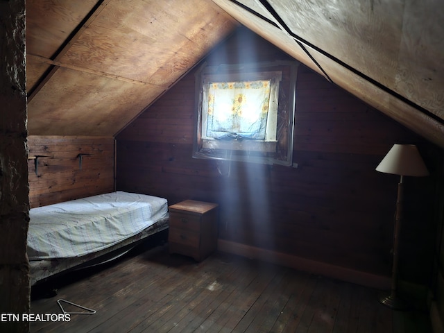 bedroom with vaulted ceiling, wooden walls, and hardwood / wood-style floors