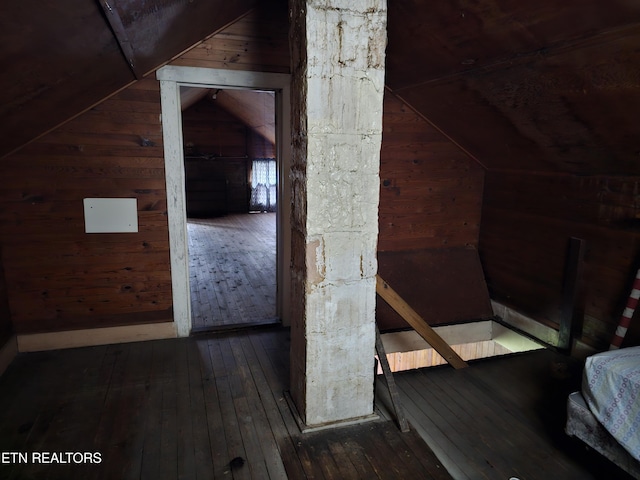 additional living space featuring dark wood-type flooring, vaulted ceiling, and wood walls