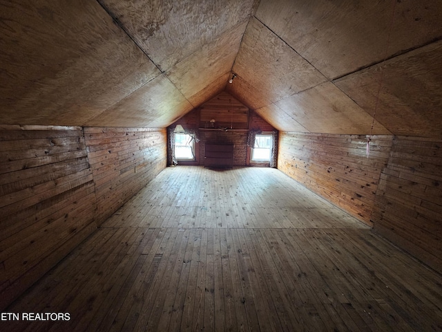 additional living space with vaulted ceiling, hardwood / wood-style floors, and wood walls