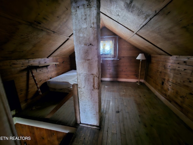 additional living space with vaulted ceiling, dark hardwood / wood-style floors, and wooden walls