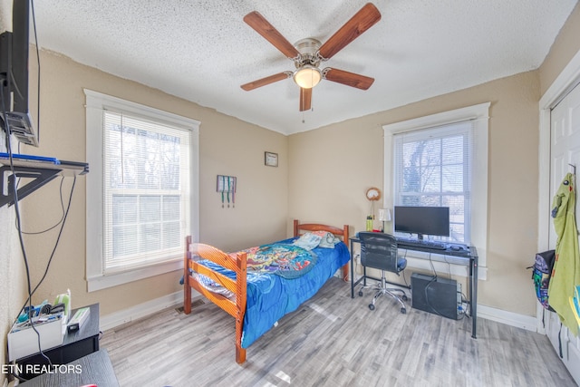 bedroom featuring ceiling fan, a textured ceiling, and light hardwood / wood-style flooring