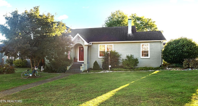 view of front of property featuring brick siding, a chimney, and a front yard