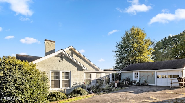 view of side of home with a garage, driveway, and a chimney