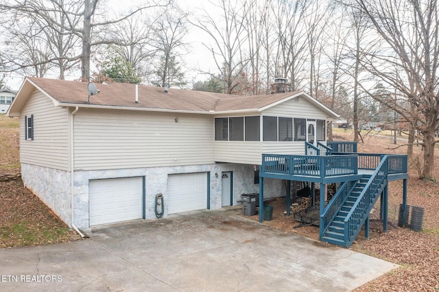 back of house with a garage, a deck, and a sunroom