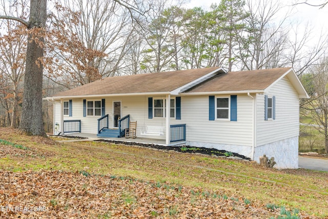 ranch-style home featuring covered porch and a front lawn