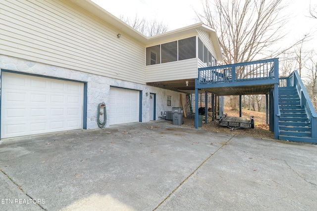 exterior space with a garage, a wooden deck, a sunroom, and central AC