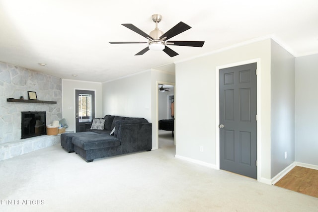 carpeted living room featuring crown molding, ceiling fan, and a stone fireplace