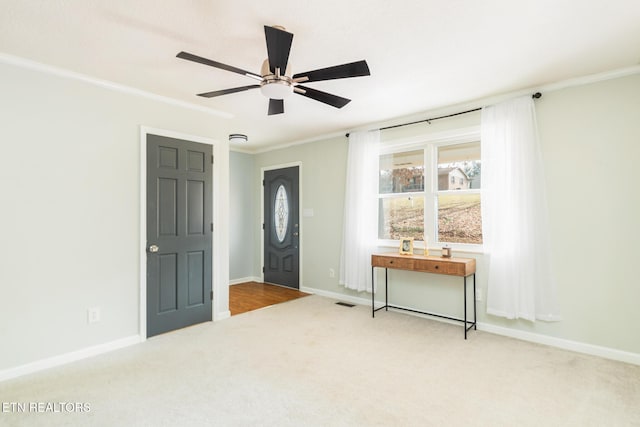 entryway featuring crown molding, ceiling fan, and carpet flooring