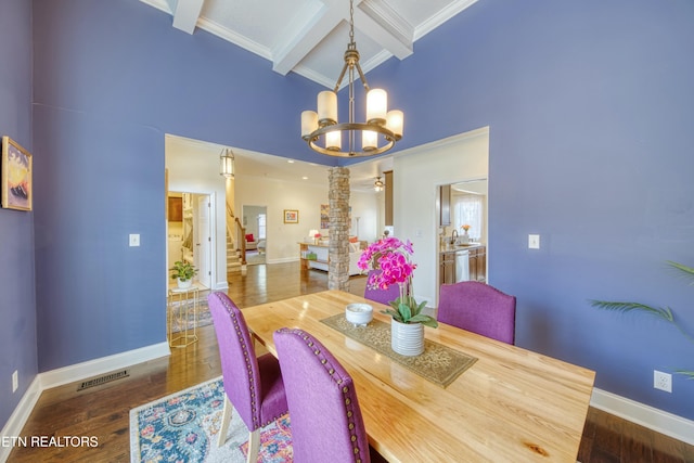 dining space with beam ceiling, coffered ceiling, dark hardwood / wood-style flooring, a chandelier, and ornate columns