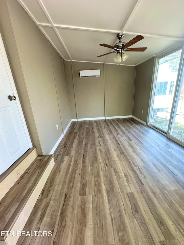 empty room with ceiling fan, wood-type flooring, and a wall unit AC