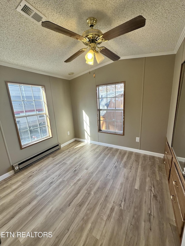 spare room featuring a baseboard radiator, ornamental molding, a textured ceiling, and light hardwood / wood-style flooring