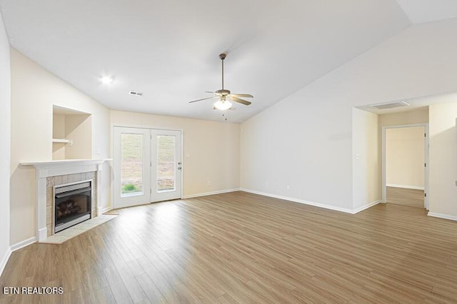 unfurnished living room featuring a tile fireplace, lofted ceiling, wood-type flooring, and ceiling fan