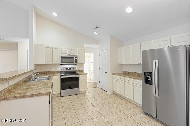 kitchen featuring sink, white cabinetry, stainless steel appliances, vaulted ceiling, and kitchen peninsula