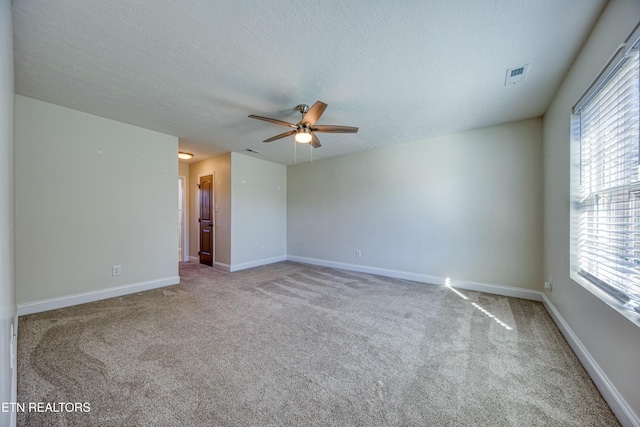 empty room with baseboards, visible vents, a textured ceiling, and light colored carpet