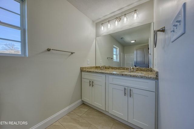 full bathroom featuring double vanity, baseboards, and a sink