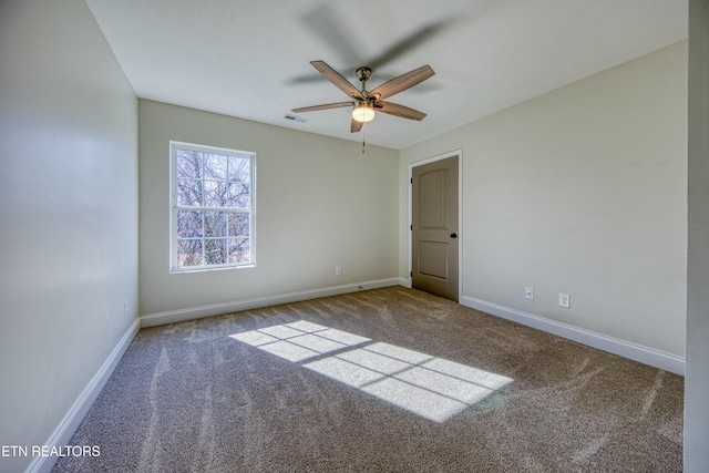 unfurnished room with carpet, visible vents, ceiling fan, and baseboards