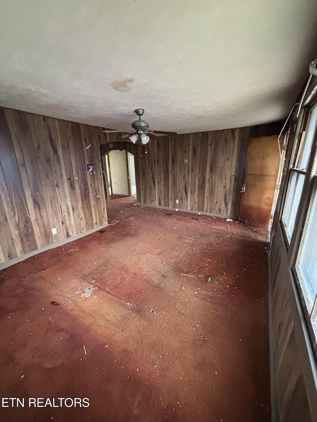 empty room featuring wooden walls and a textured ceiling