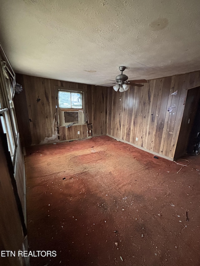 spare room featuring cooling unit, a textured ceiling, and wood walls