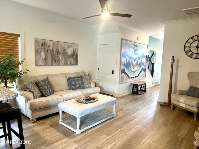 living room featuring ornamental molding, light hardwood / wood-style floors, and ceiling fan