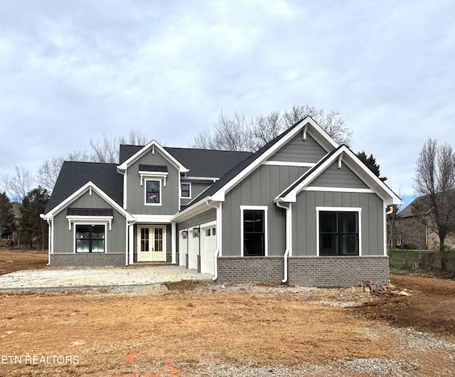 view of front of property featuring board and batten siding, a garage, brick siding, and driveway