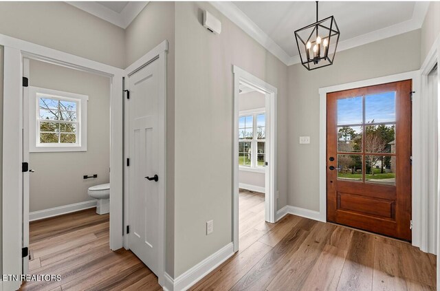 foyer entrance with crown molding, an inviting chandelier, and light hardwood / wood-style floors