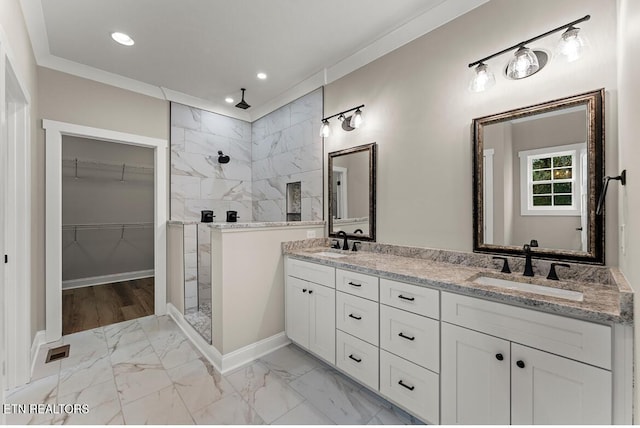 bathroom with a tile shower, vanity, and crown molding