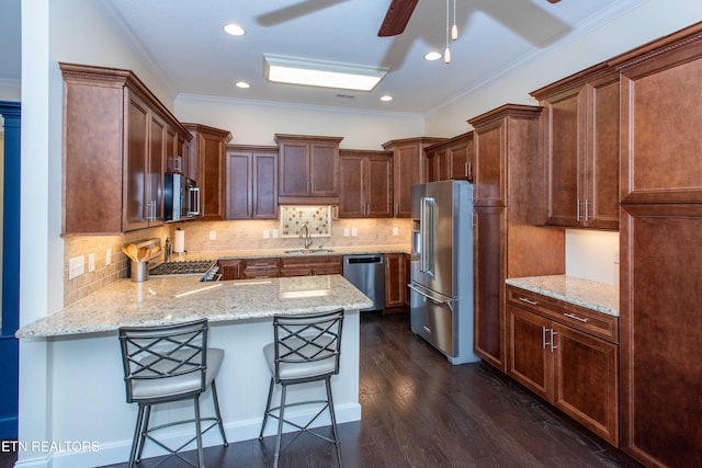 kitchen featuring sink, a breakfast bar area, light stone counters, dark hardwood / wood-style floors, and stainless steel appliances