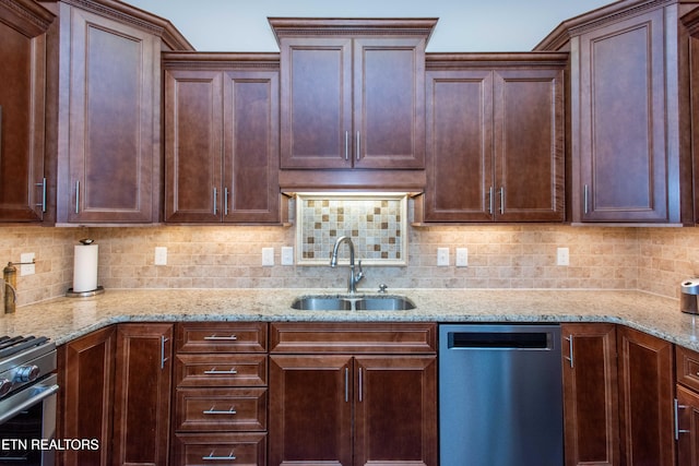 kitchen with appliances with stainless steel finishes, sink, light stone counters, and decorative backsplash