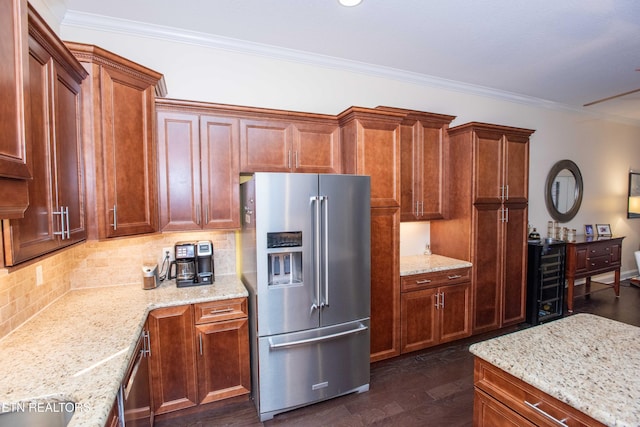 kitchen with light stone counters, dark wood-type flooring, ornamental molding, and high end refrigerator