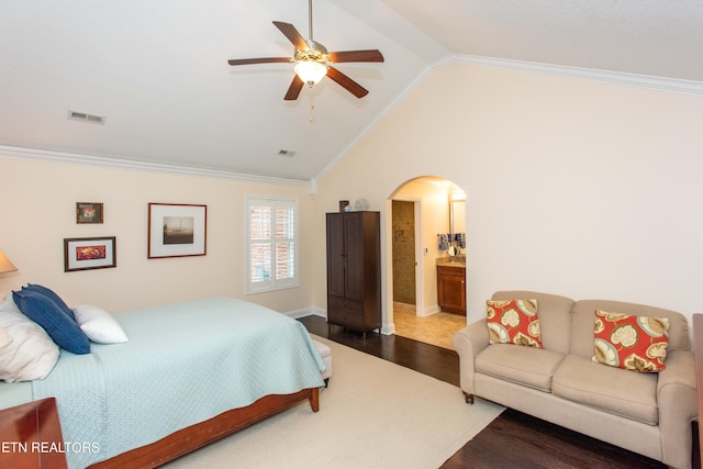 bedroom featuring lofted ceiling, crown molding, ensuite bath, ceiling fan, and wood-type flooring