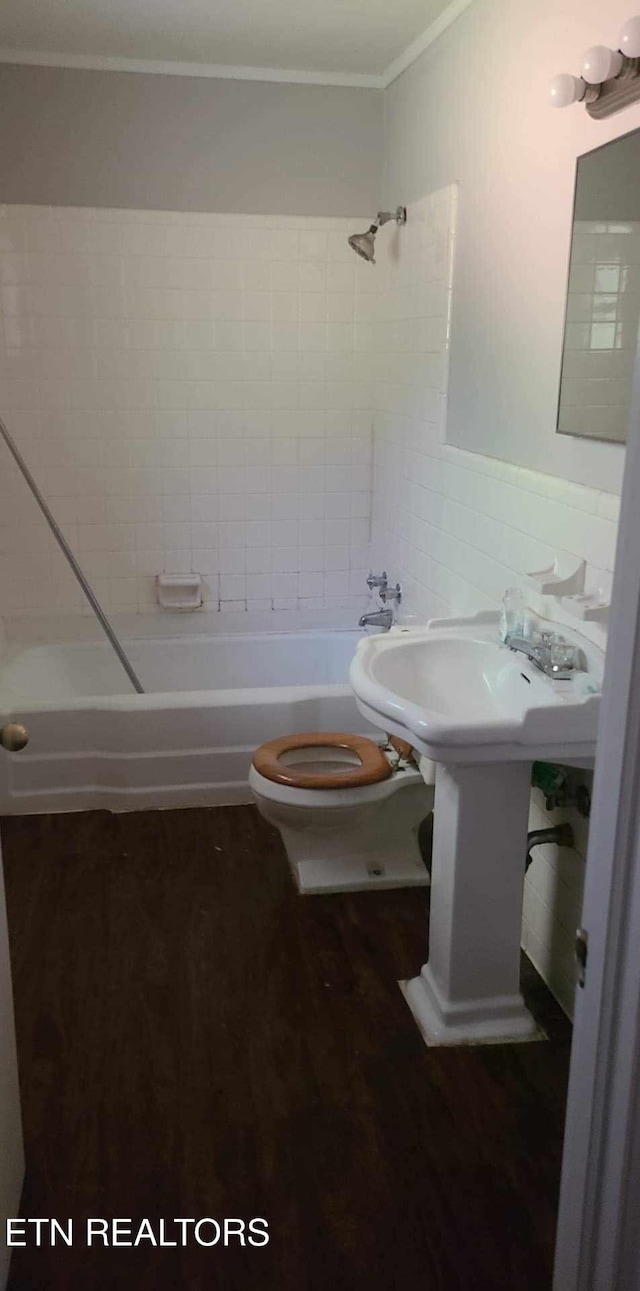 bathroom featuring tile walls, hardwood / wood-style floors, tiled shower / bath combo, ornamental molding, and toilet