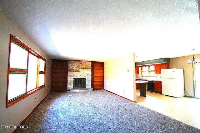 unfurnished living room with built in features, an inviting chandelier, a fireplace, and a textured ceiling