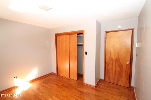 unfurnished bedroom with light hardwood / wood-style flooring and a closet