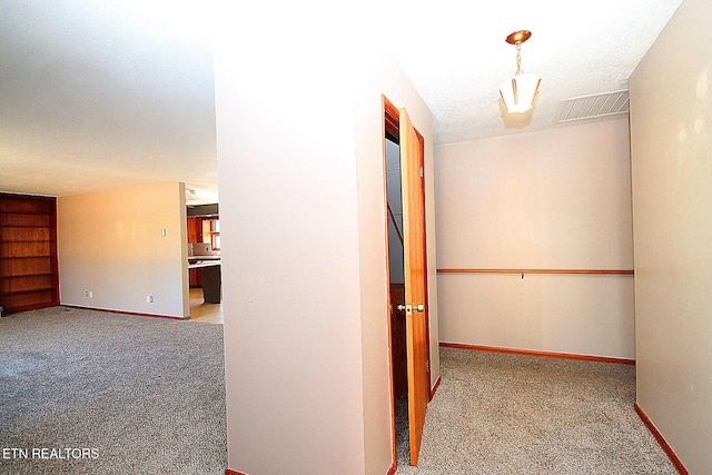 corridor with light colored carpet, a textured ceiling, and built in shelves