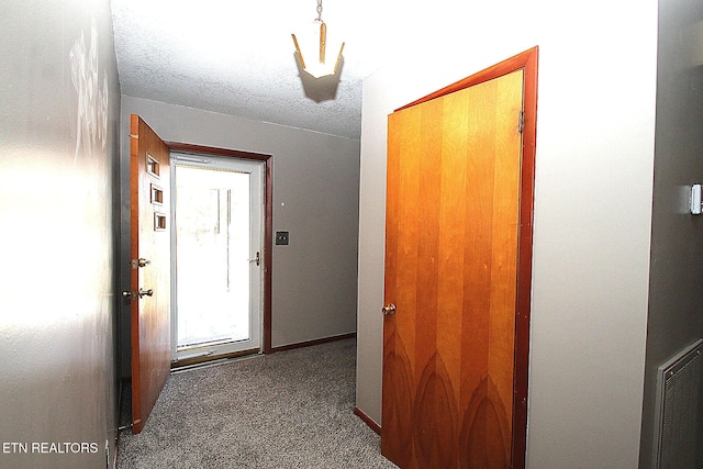 hallway with carpet and a textured ceiling