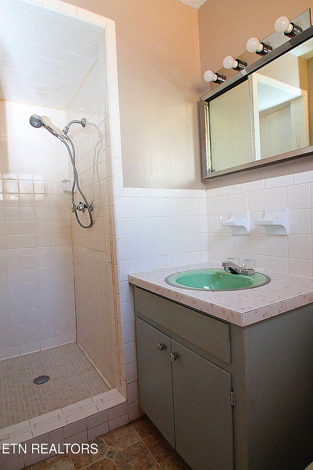 bathroom with tile walls, vanity, and a tile shower