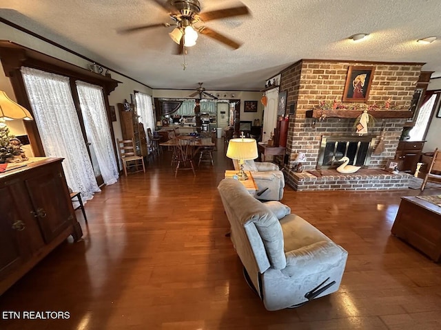 living room featuring ceiling fan, dark hardwood / wood-style flooring, a textured ceiling, and a fireplace