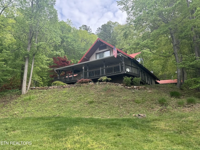 view of front facade featuring a front yard, a wooded view, and a deck