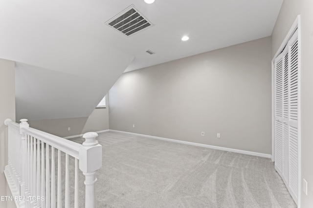 additional living space featuring vaulted ceiling and light carpet