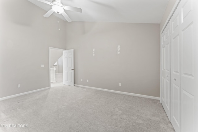 unfurnished bedroom with high vaulted ceiling, light colored carpet, a closet, and ceiling fan