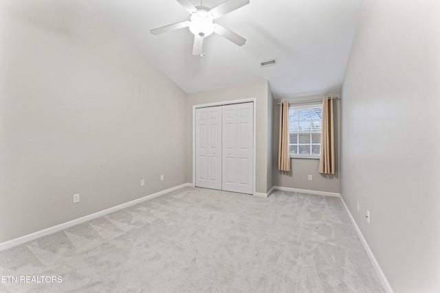 unfurnished bedroom featuring vaulted ceiling, light carpet, ceiling fan, and a closet