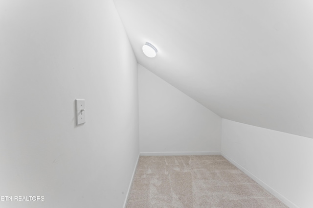 bonus room with vaulted ceiling and light colored carpet