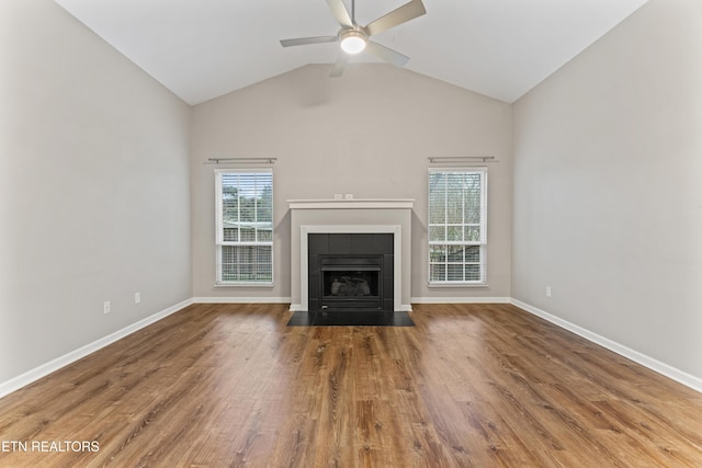 unfurnished living room featuring vaulted ceiling, ceiling fan, a tiled fireplace, and hardwood / wood-style floors