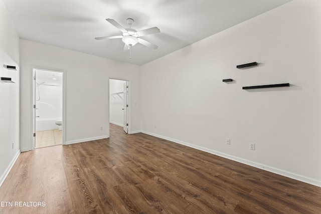 unfurnished bedroom with ceiling fan, a walk in closet, ensuite bathroom, and dark hardwood / wood-style flooring