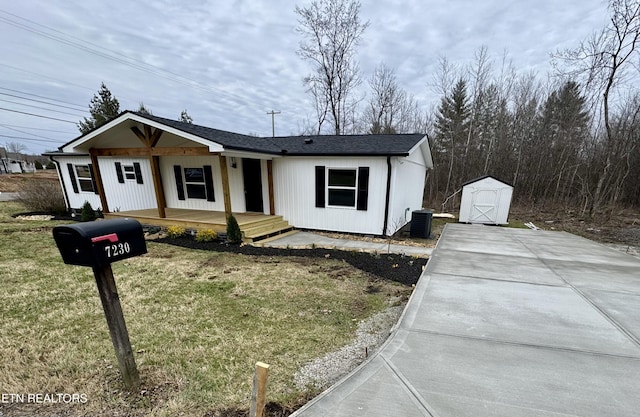 view of front of home featuring central AC unit, a storage unit, and a front lawn