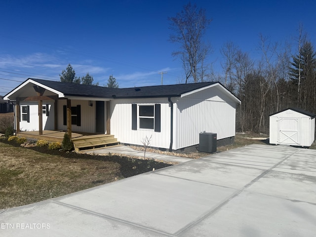 view of front facade with covered porch, an outdoor structure, central AC unit, and a shed